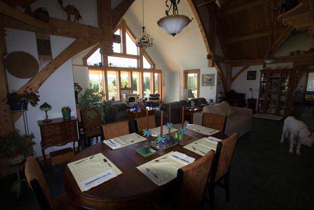 Cozy dining room with a large wooden table, papers, hanging lights, and a white dog near the doorway