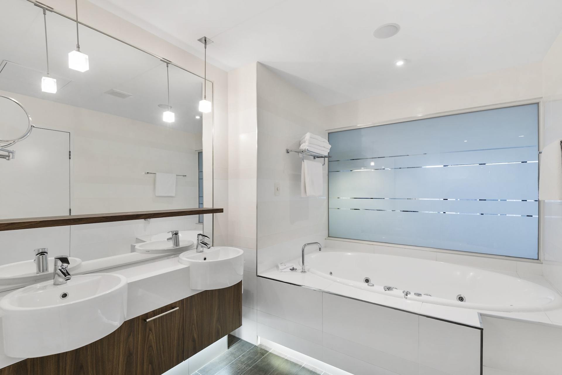 Modern bathroom with a double sink vanity, bathtub, and frosted window.