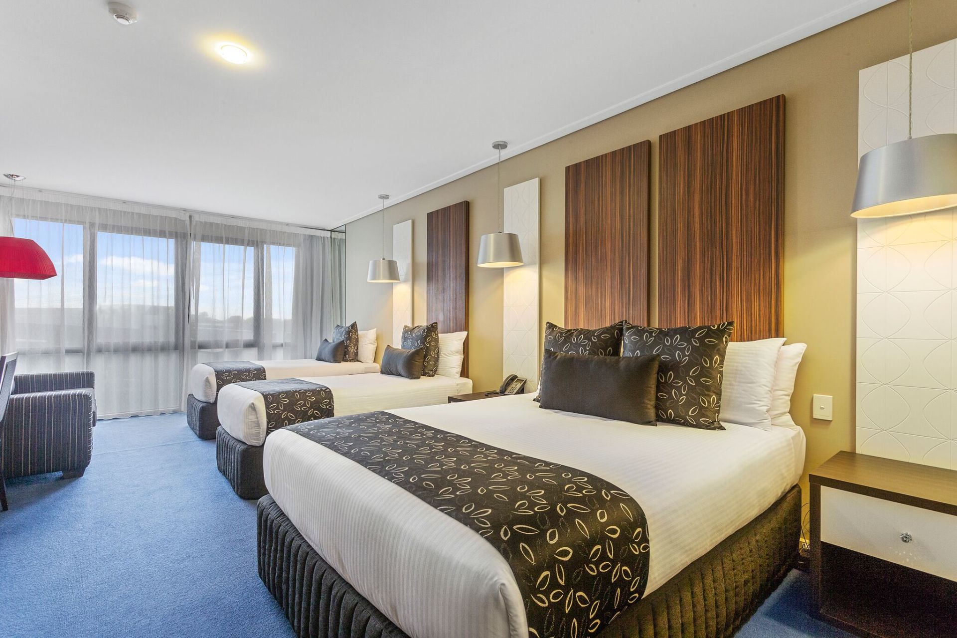 Hotel room with two queen beds, brown wood headboards, and blue carpet.