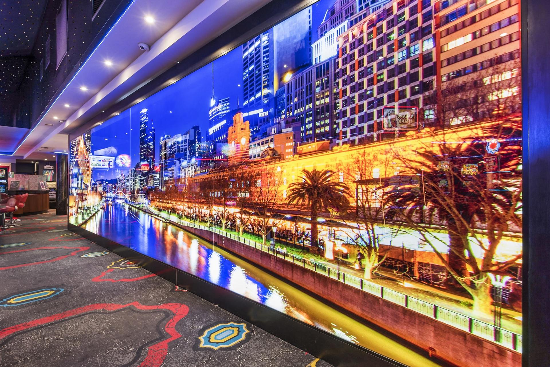 Large LED screen displaying a night city scene with water, palm trees, and buildings.