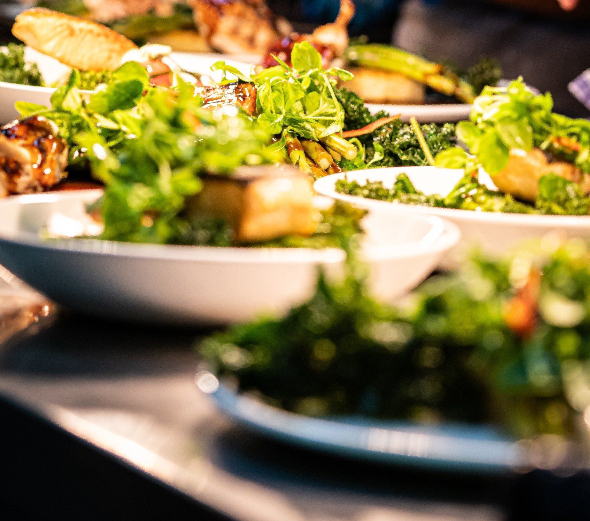 Plates of food with green salads, prepared on a countertop, ready to serve.