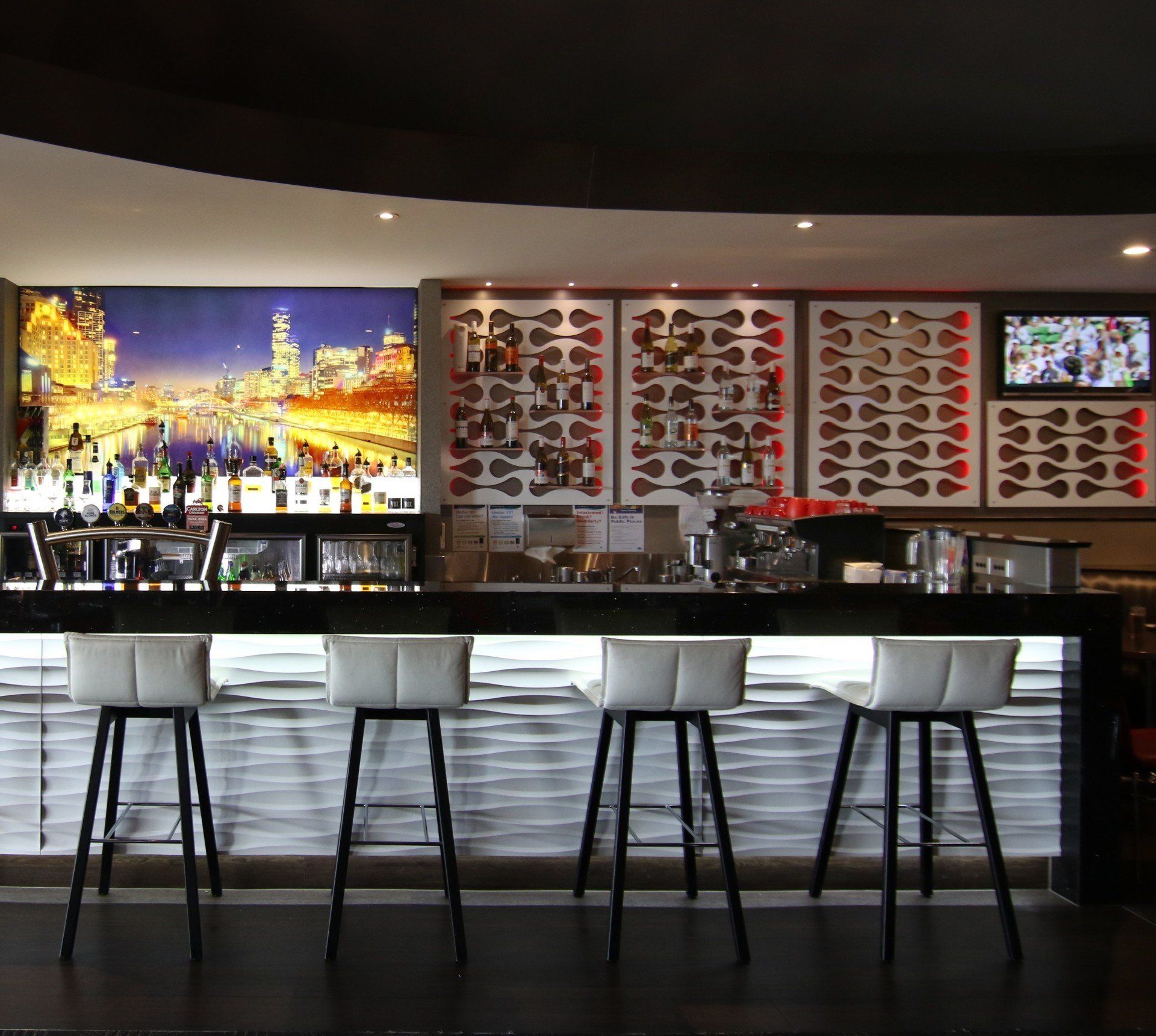 Bar with four white bar stools, bottles, city backdrop, and guitar decor.