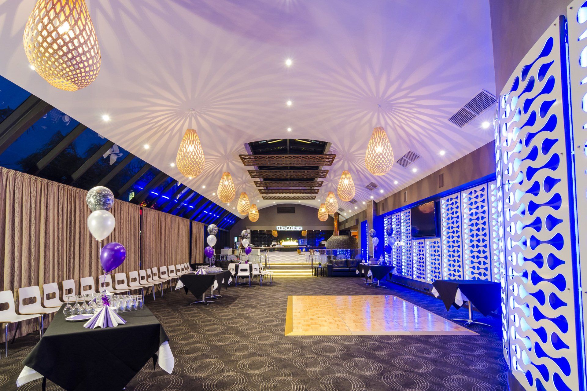 Elegant banquet hall with tables, chairs, and dance floor, decorated with gold lights and blue accents.
