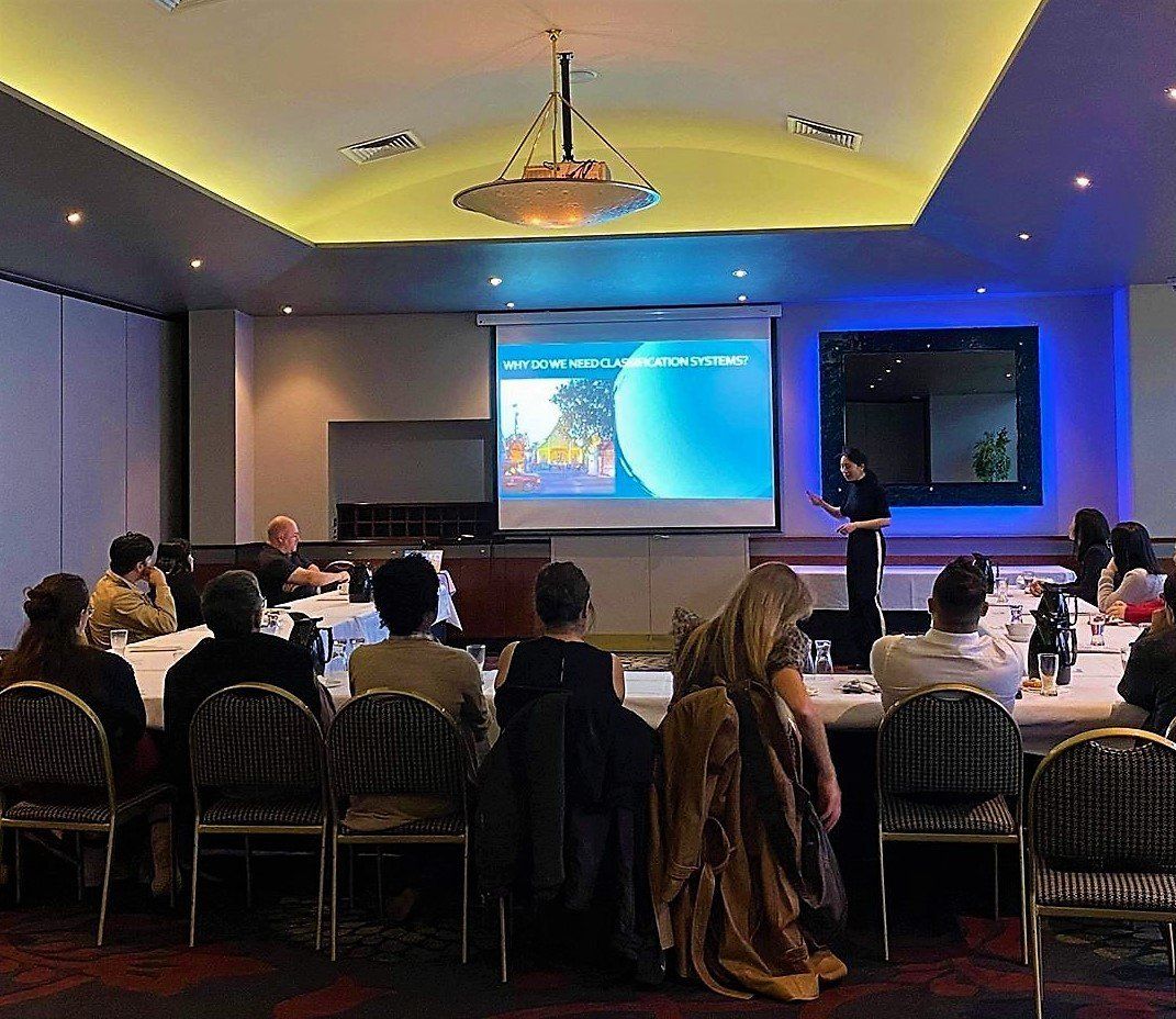 A presentation in a conference room with an audience. A person stands at the screen, giving a talk.