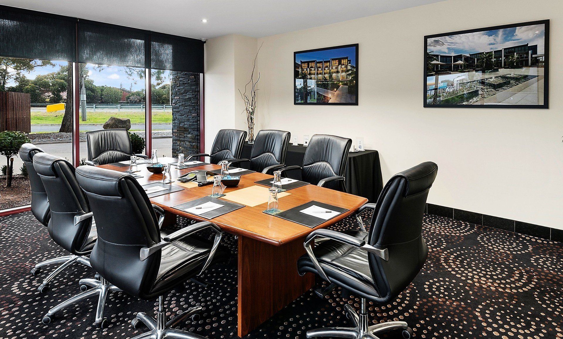 A conference room with a large table surrounded by black chairs, natural light, and views.