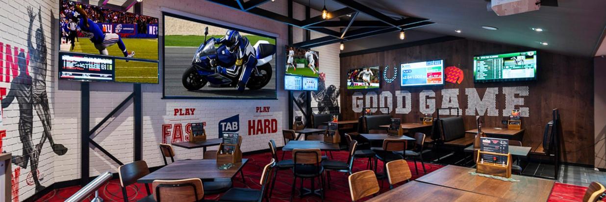 Sports bar interior with multiple screens displaying sports, tables, and 