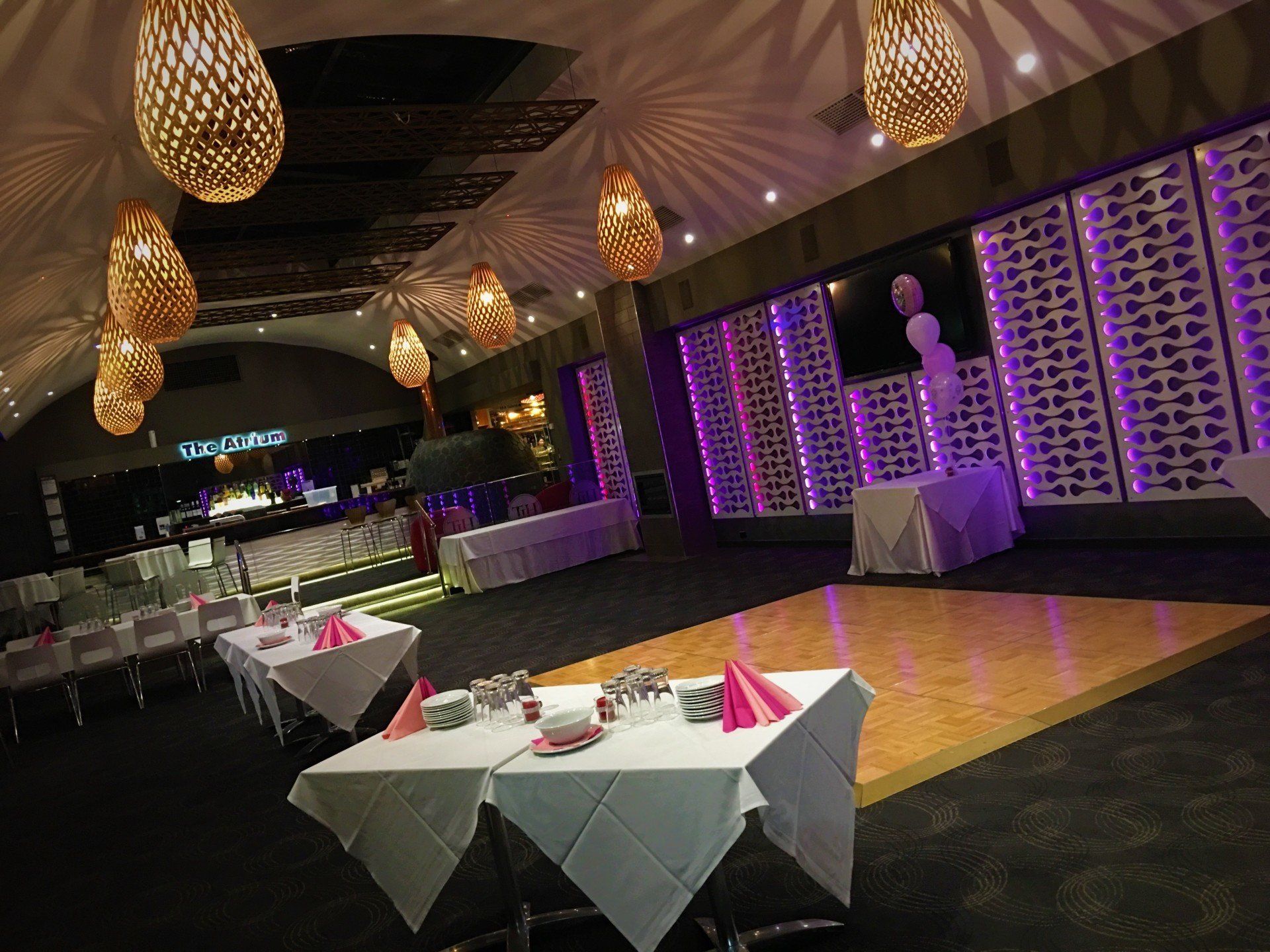 Formal event space with tables, dance floor, decorative lighting, and purple accents.