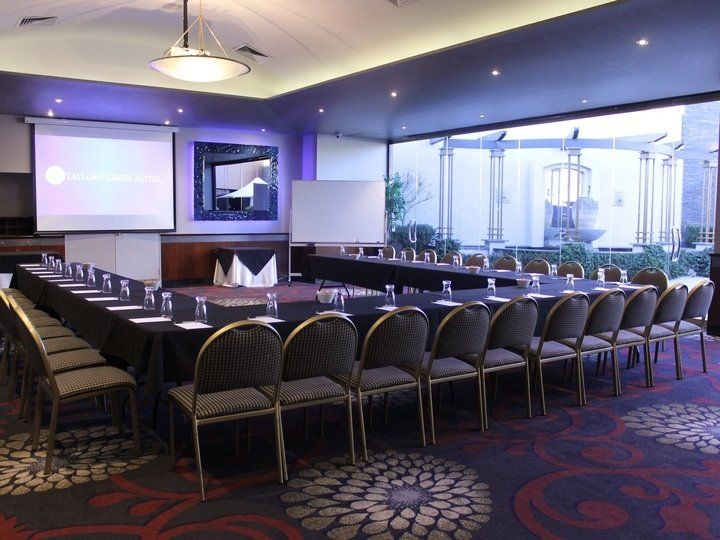 Conference room with U-shaped table, chairs, projectors, and exterior view.