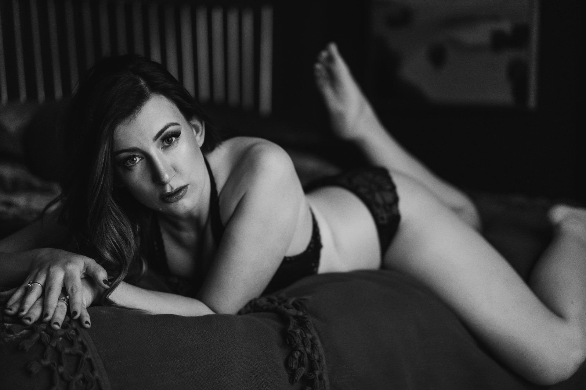 boudoir image of woman on bed with foot in air, looking at camera