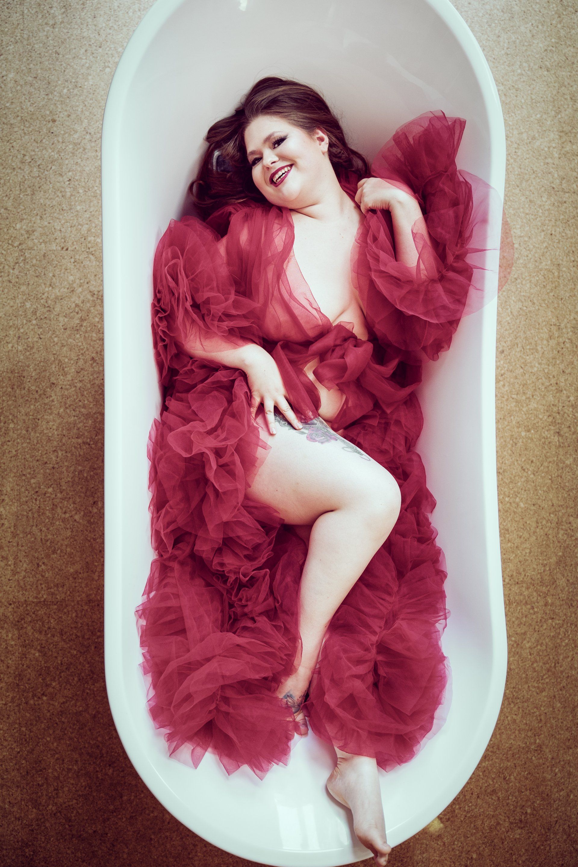top down boudoir image of woman in bathtub wearing red robe