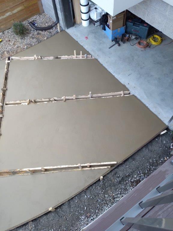 Large tan tarp or fabric spread over a driveway, weighted down with bamboo poles and clips.