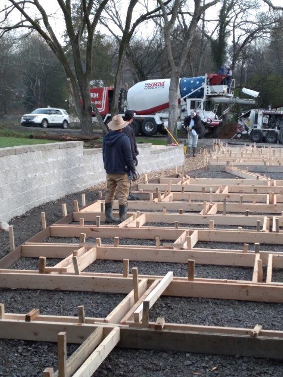 Workers framing a concrete foundation at a construction site with a truck in the background