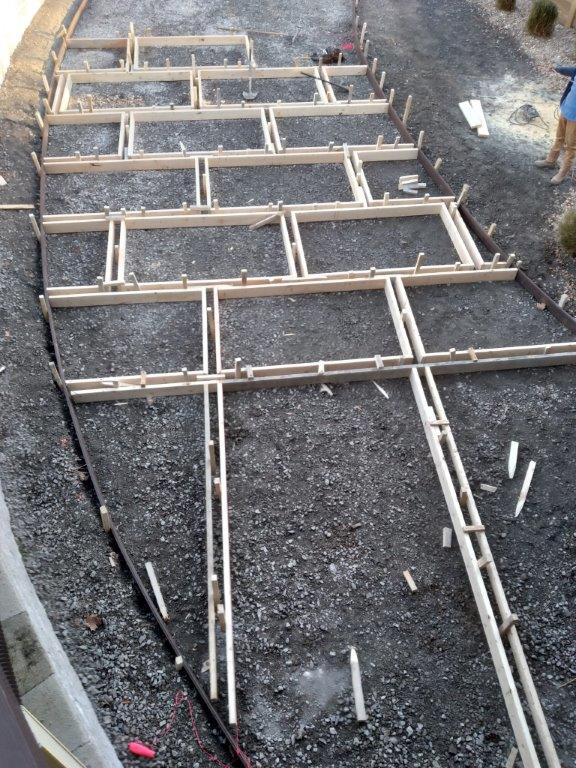 Wooden framework laid over gravel for a retaining wall or deck foundation, viewed from above