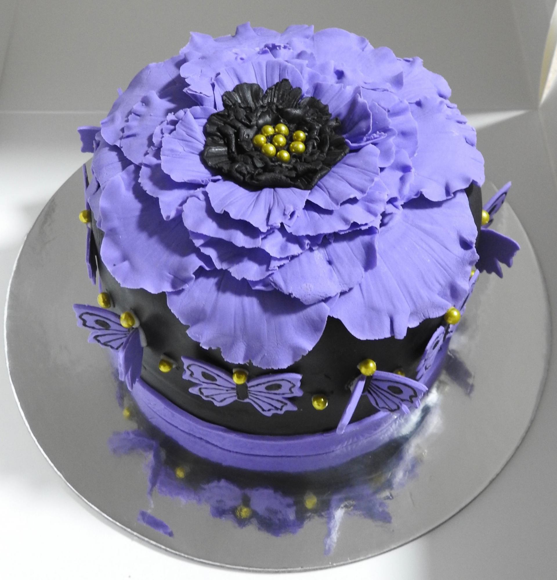 Small purple and black birthday cake with artistic style flower and butterflies