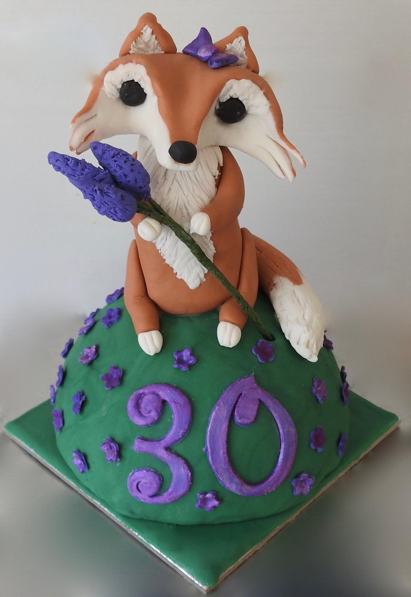 Cute Fox Cake Topper, holding a bunch of lavender, sitting on a green hill with purple flowers