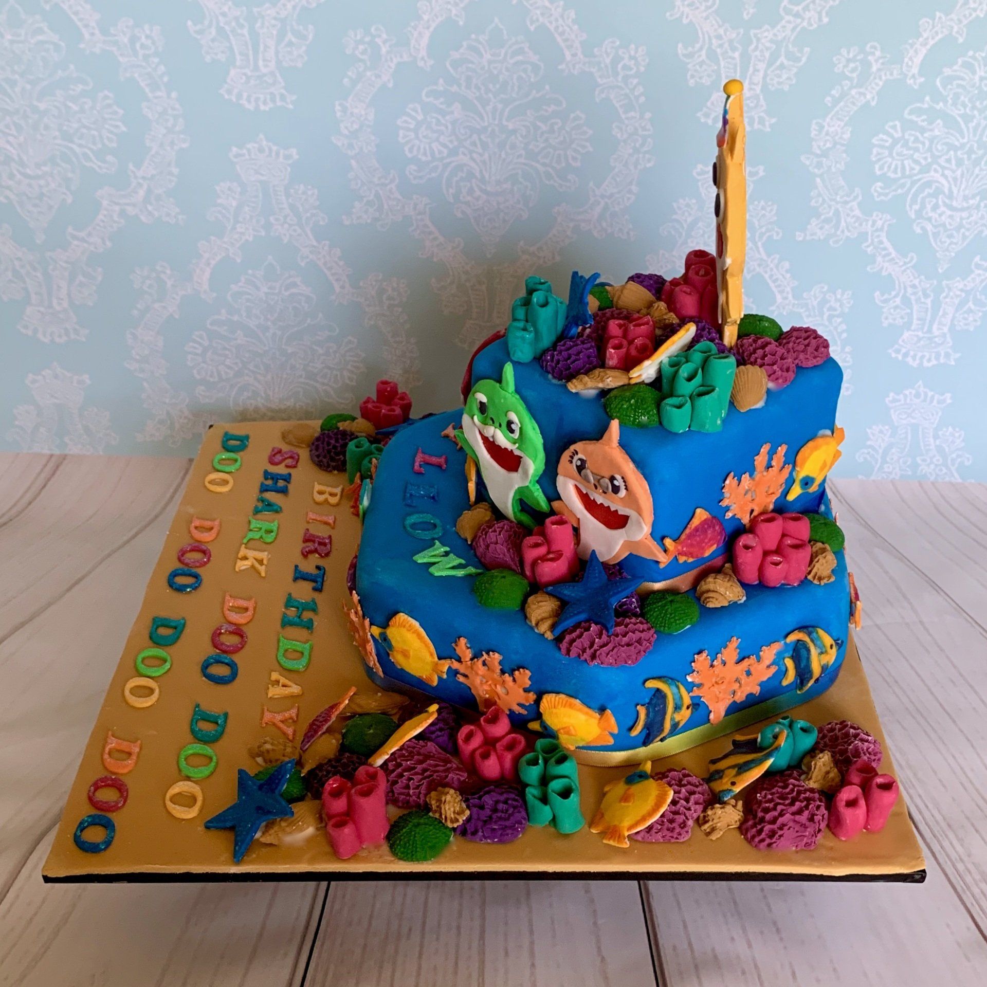 1st birthday cake. Famous hand cut fondant shark charchaters, lots of fondant coral, shells, fish and fondant sentiments. Side 1 view