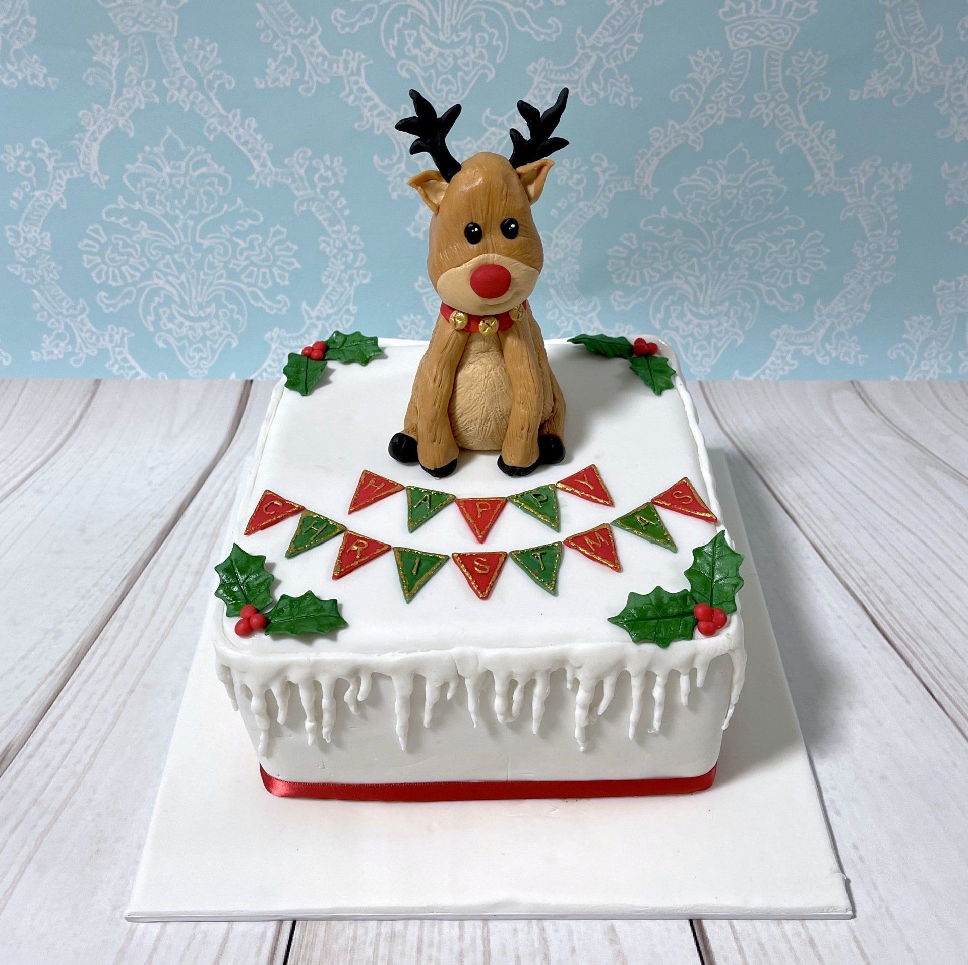 Christmas cake with white fondant, fondant holly, the words 