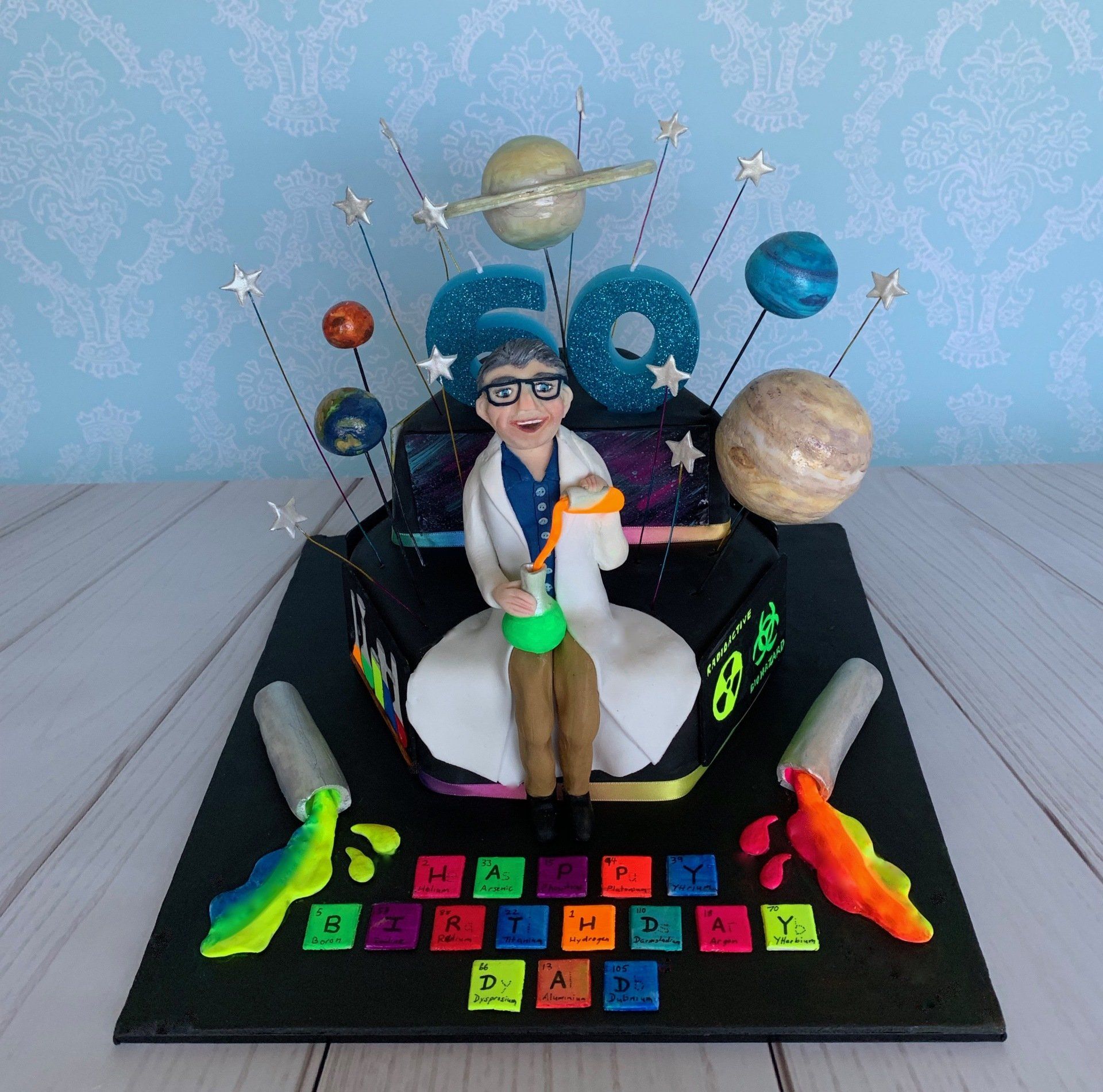A tiered hexagonalm, Science themed cake with Planets, A mad scientist figure, and lots of other science related details. Front natural light.