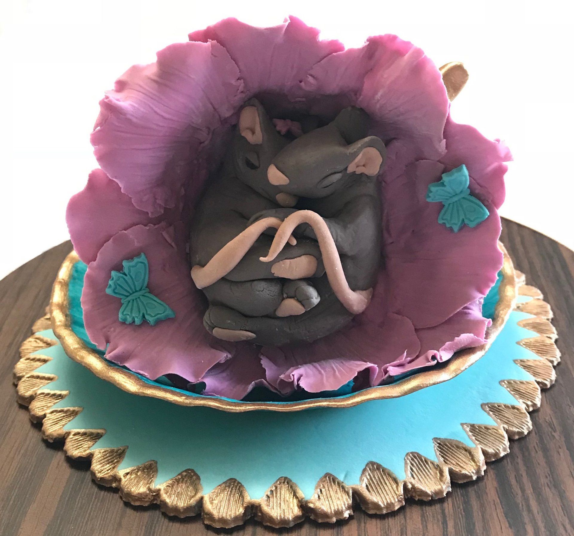 Cake topper of two very cute mice sleeping in a flower inside an ornate teacup.all made from sugar