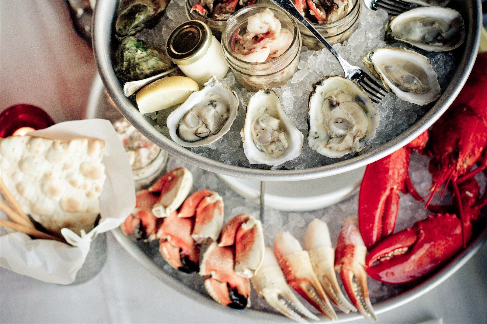 Seafood platter with oysters, crab legs, shrimp, and lemon on ice in metal trays