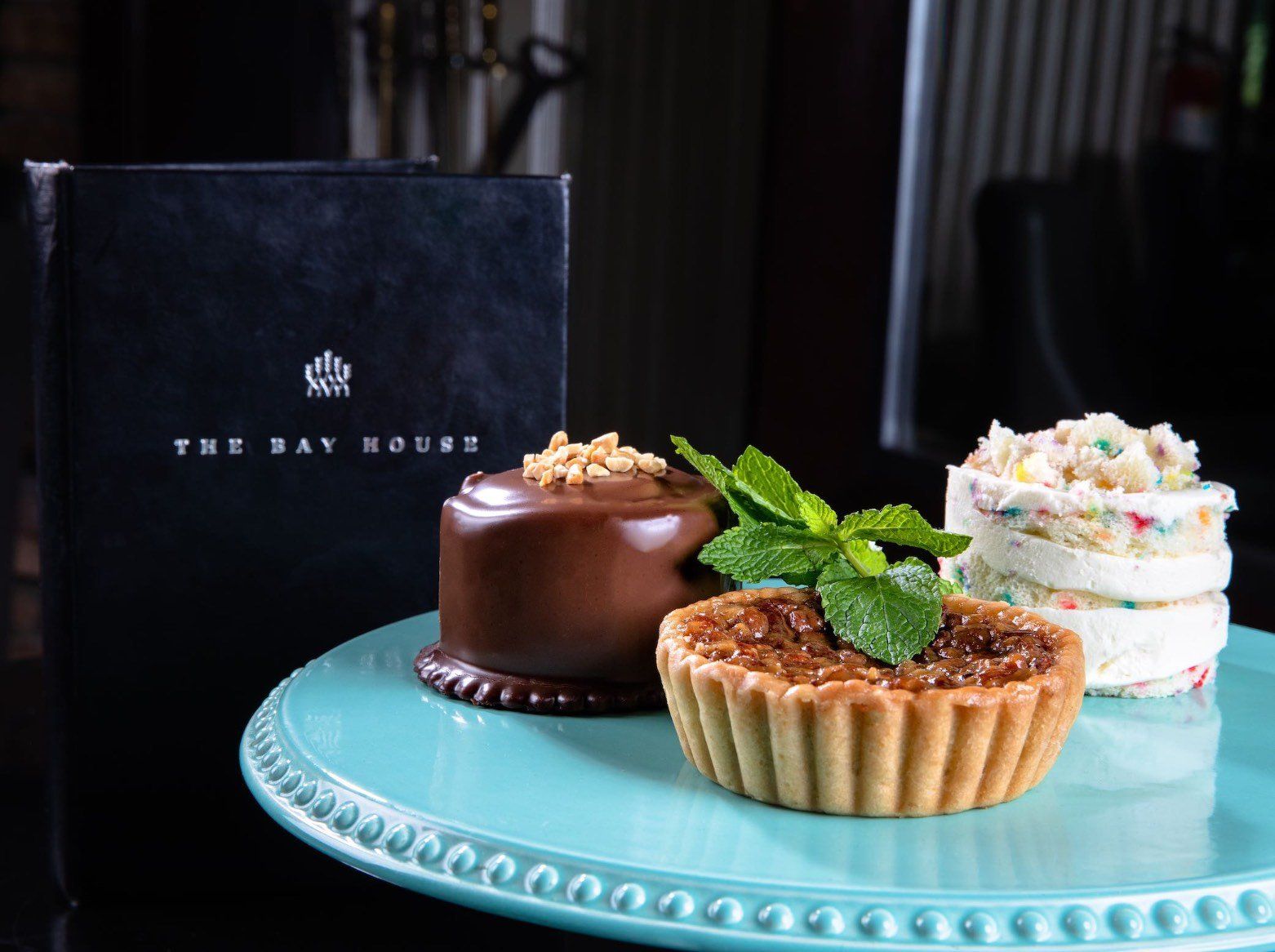 Assorted pastries on a turquoise tray beside a dark gift box