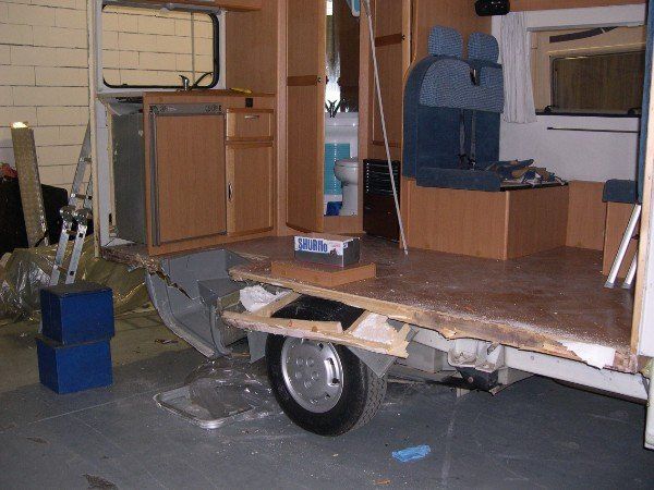Piccolo rimorchio con pianale in legno e armadietto all'interno di un'area adibita a officina/garage.