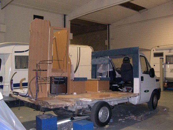 Un camion bianco carico di mobili imballati in grandi scatole e oggetti avvolti in un garage adibito a magazzino.