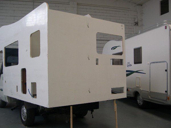 Carrozzeria bianca per roulotte in un magazzino, con un altro camper parcheggiato accanto.