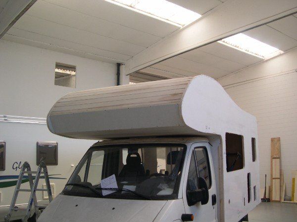 Camper bianco con tetto rialzato all'interno di un'officina/garage
