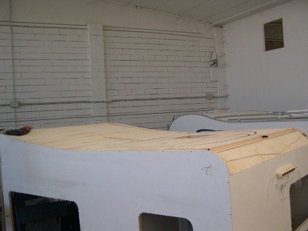 Apparecchiatura o contenitore rettangolare bianco in una stanza spoglia con pareti in mattoni e finestre a persiana.