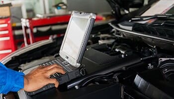 Man Repairing Car using laptop — electrical diagnostics in Cinnaminson, NJ Man Repairing Car using laptop — electrical diagnostics in Cinnaminson, NJ