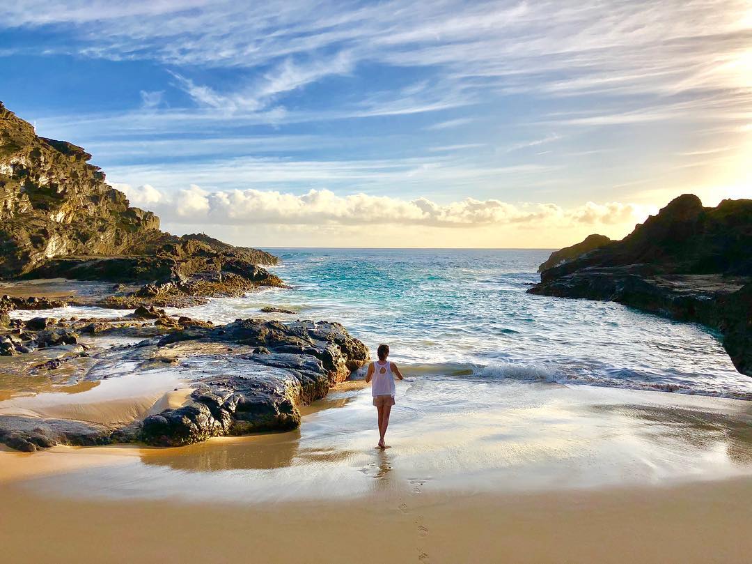 A woman is standing on a beach near the ocean.
