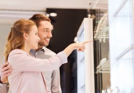 A man and a woman are looking at jewelry in a store.