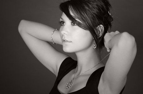 A black and white photo of a woman wearing a necklace and earrings.