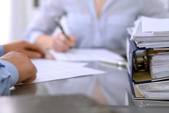 dei raccoglitori sulla scrivania e delle persone che scrivono su dei fogli