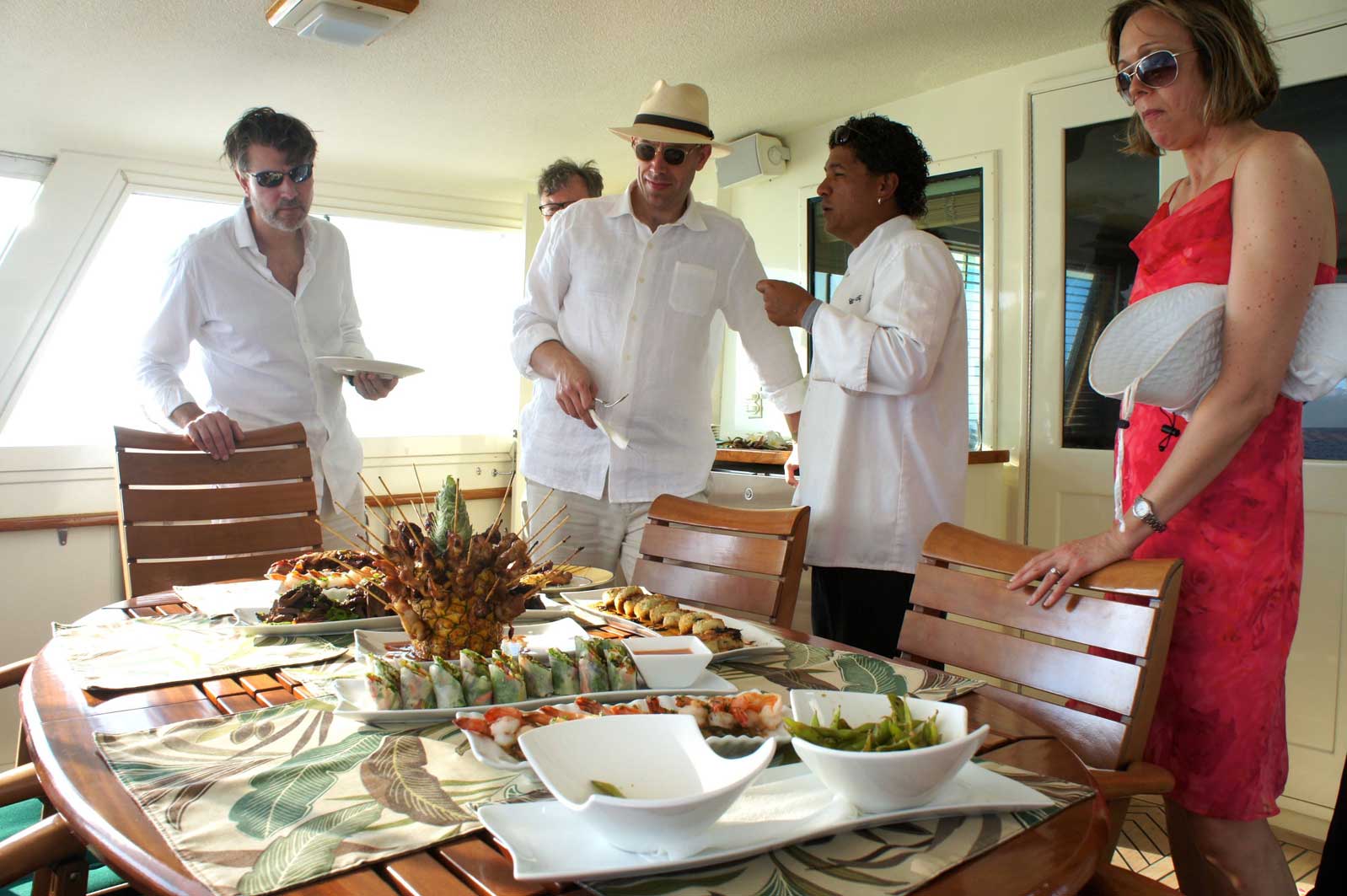 A group of people standing around a table with food on it