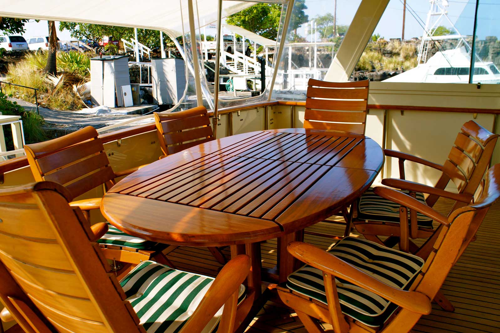 A table and chairs on a deck with a boat in the background