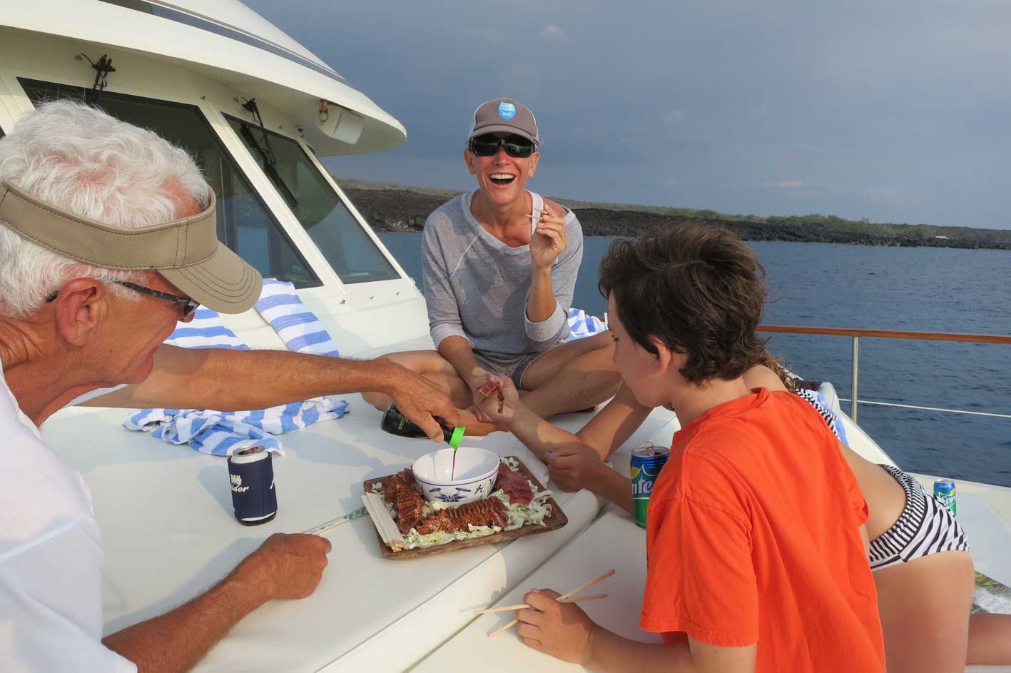 A group of people are sitting on a boat with a cake on the deck.