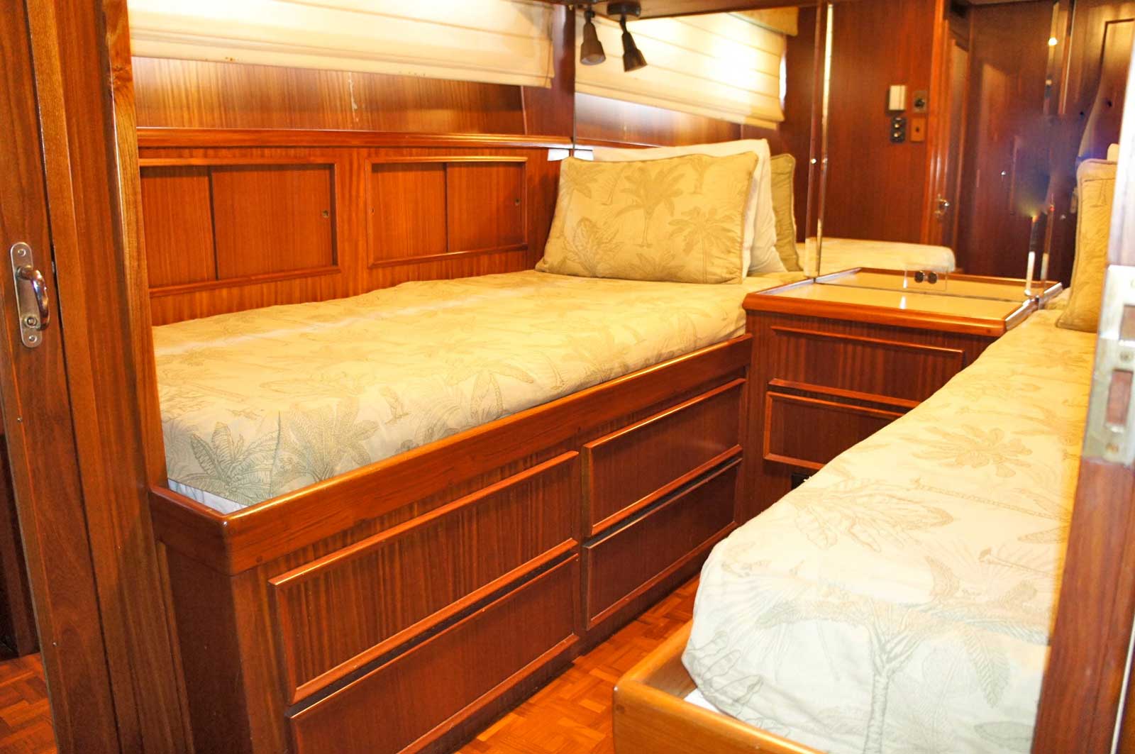 A bedroom on a boat with two beds and a nightstand.