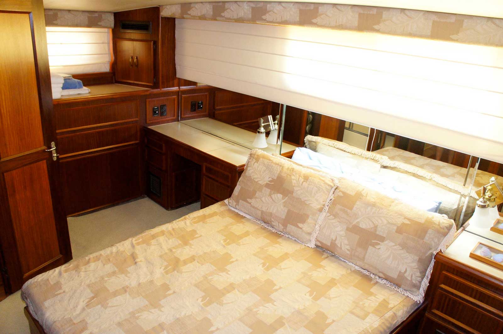 A bedroom on a boat with a large bed and a desk