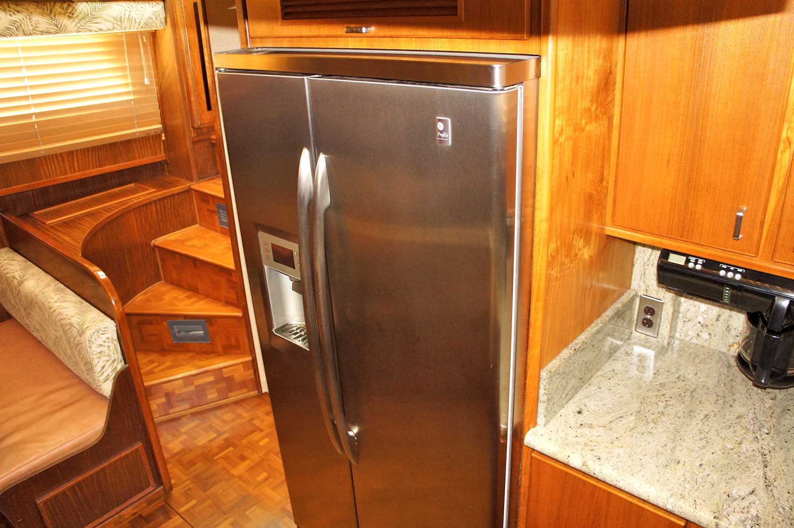 A stainless steel refrigerator in a kitchen with wooden cabinets.