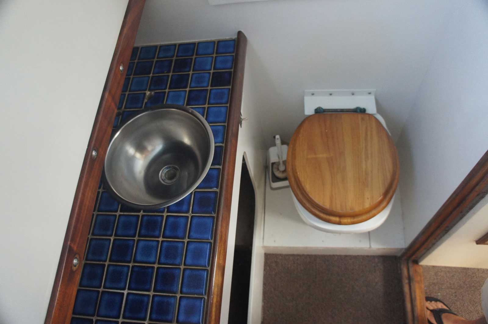 A bathroom with a wooden toilet and a stainless steel sink
