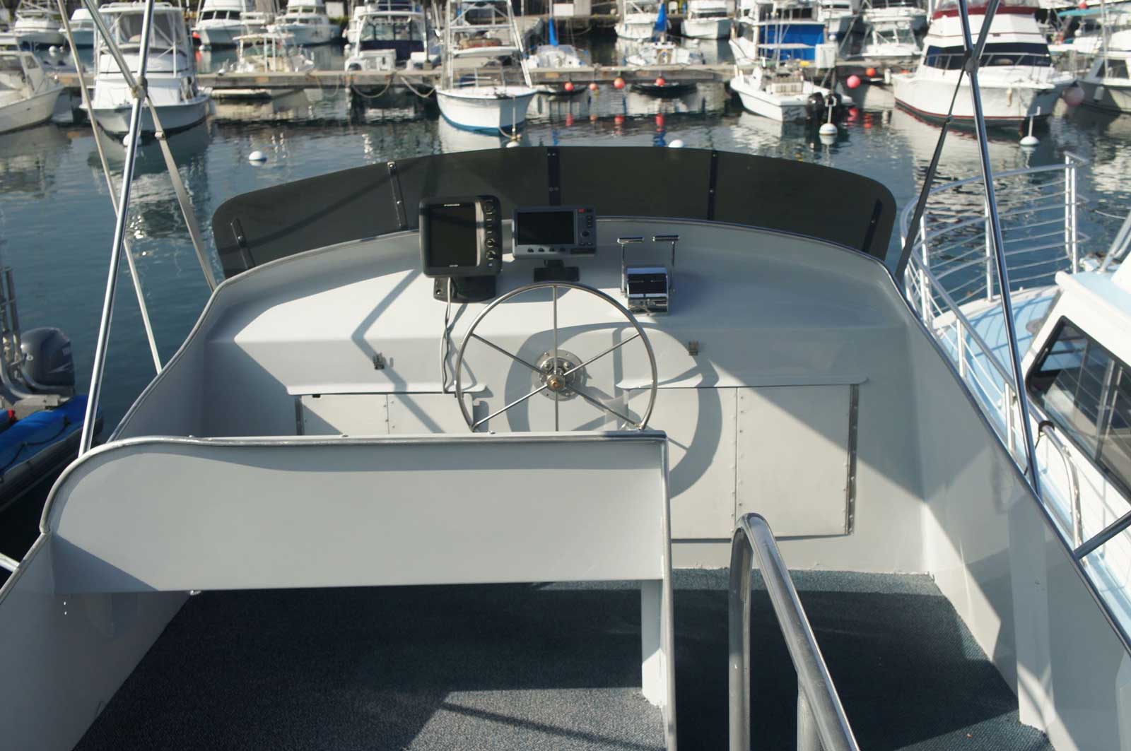 A boat with a steering wheel is docked in a marina