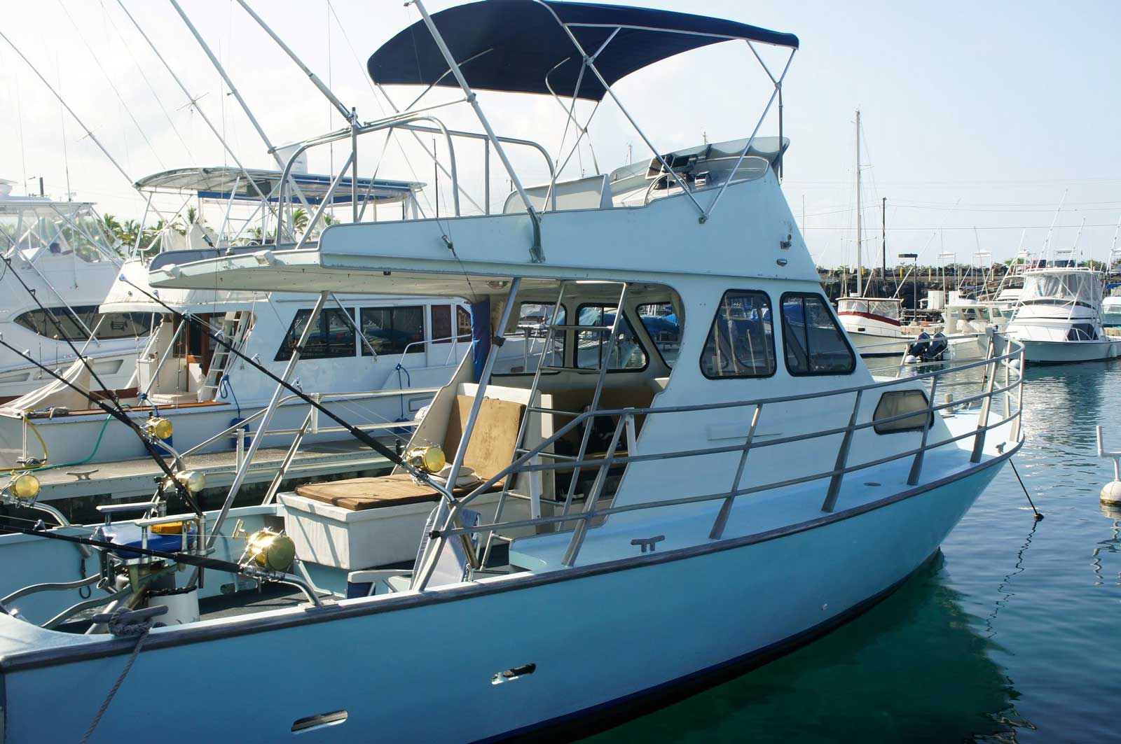 A blue boat is docked in a marina with other boats