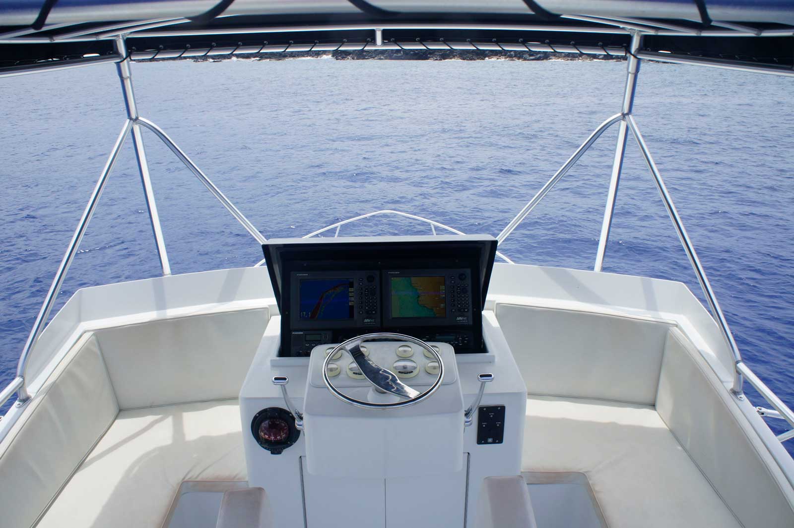 The front of a boat with a steering wheel in the water