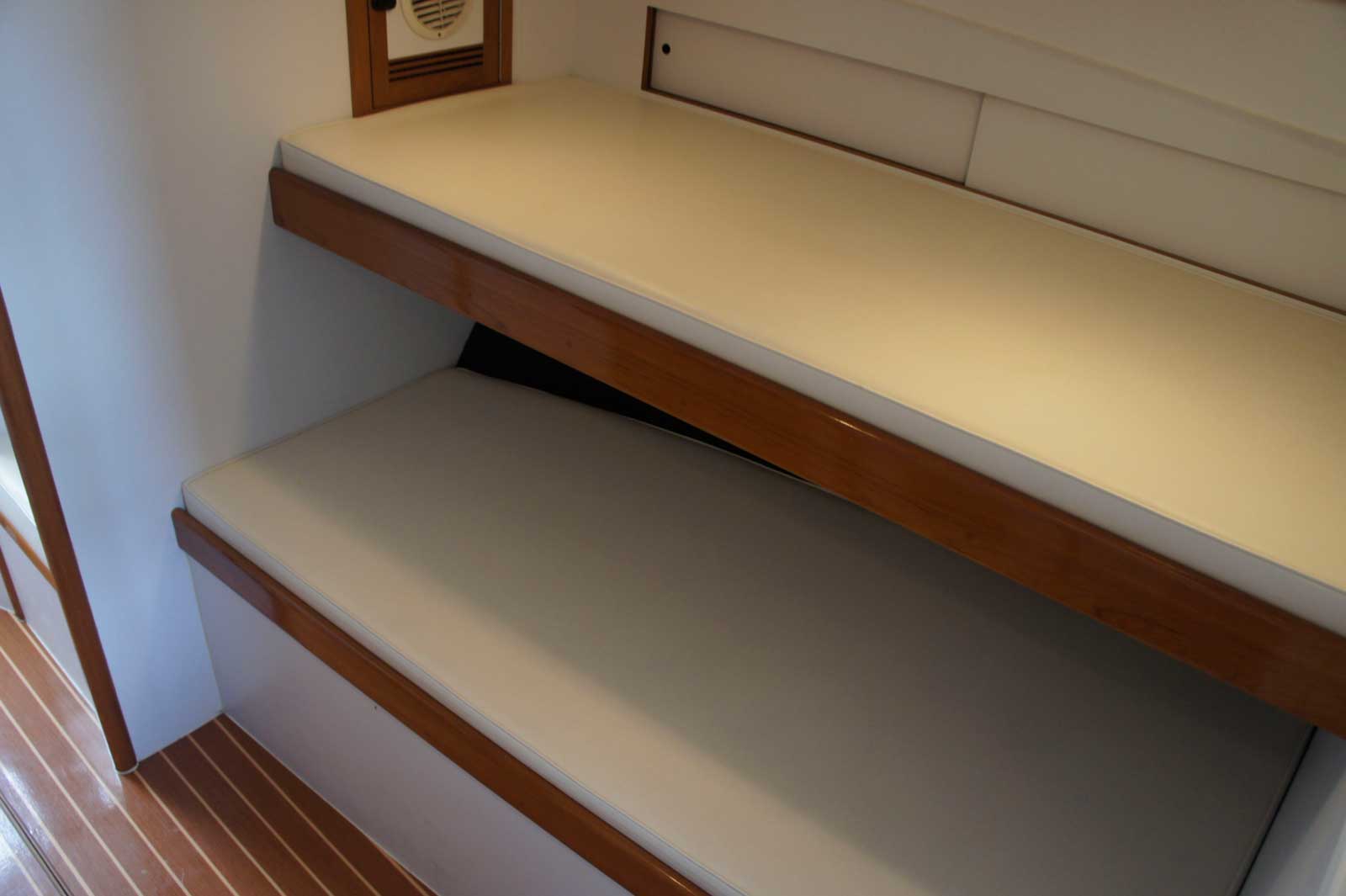 A bunk bed on a boat with a white mattress.