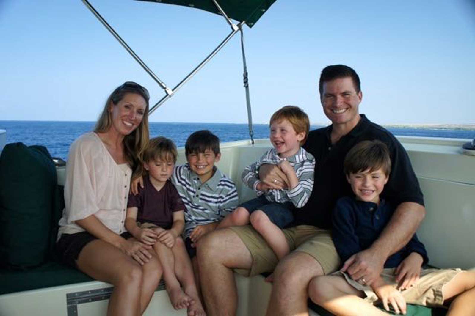 A family is posing for a picture on a boat in the ocean.