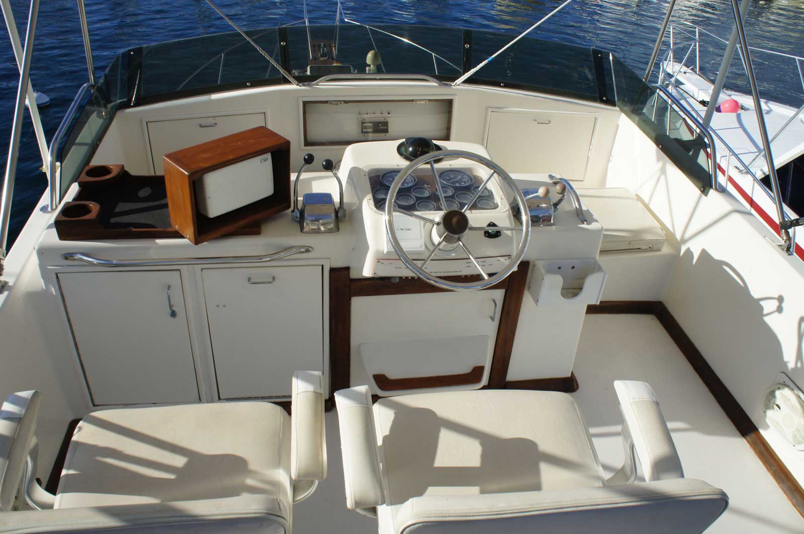 The front of a boat with a steering wheel and chairs