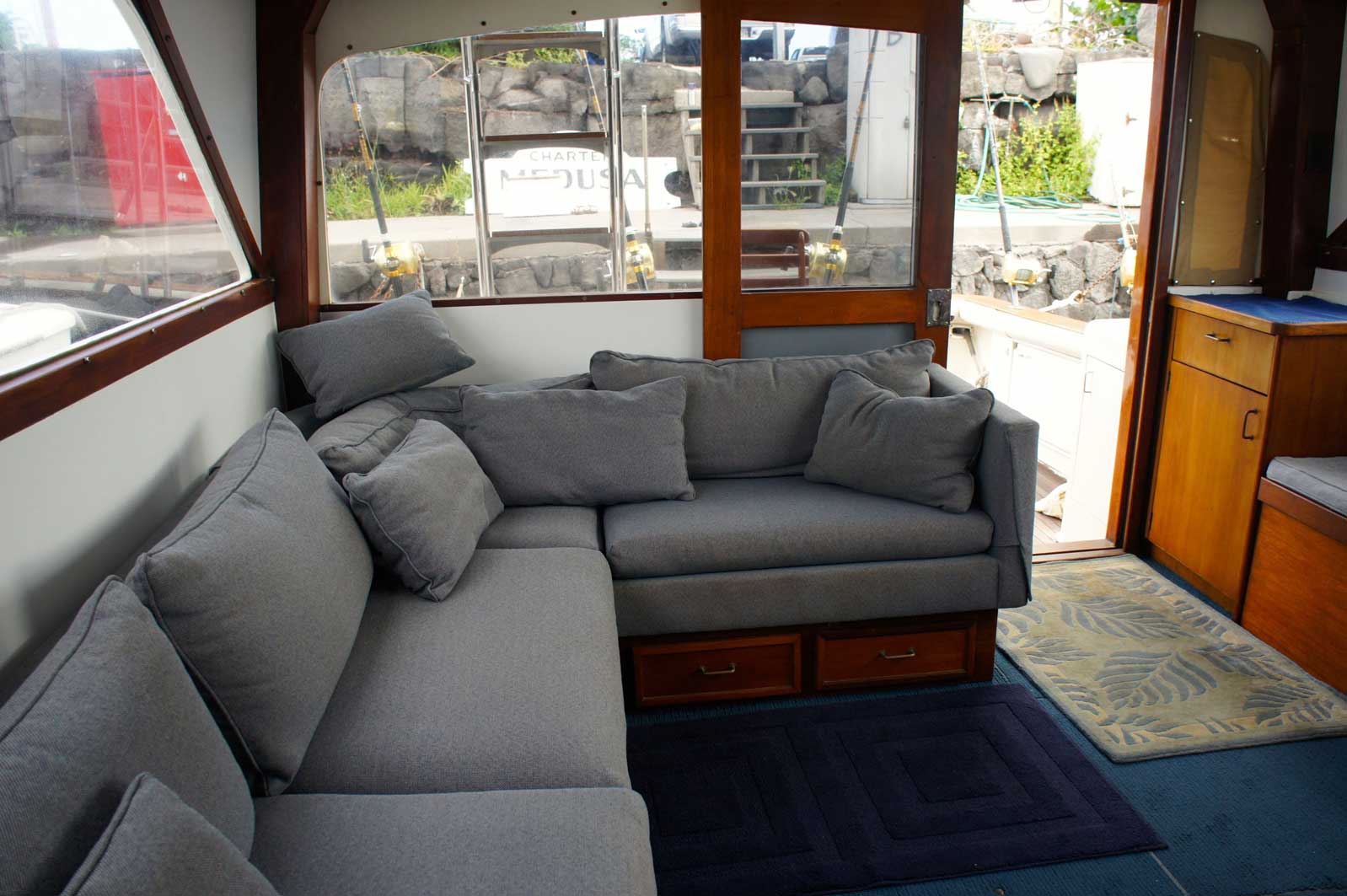 A living room with a couch and a window with a boat in the background