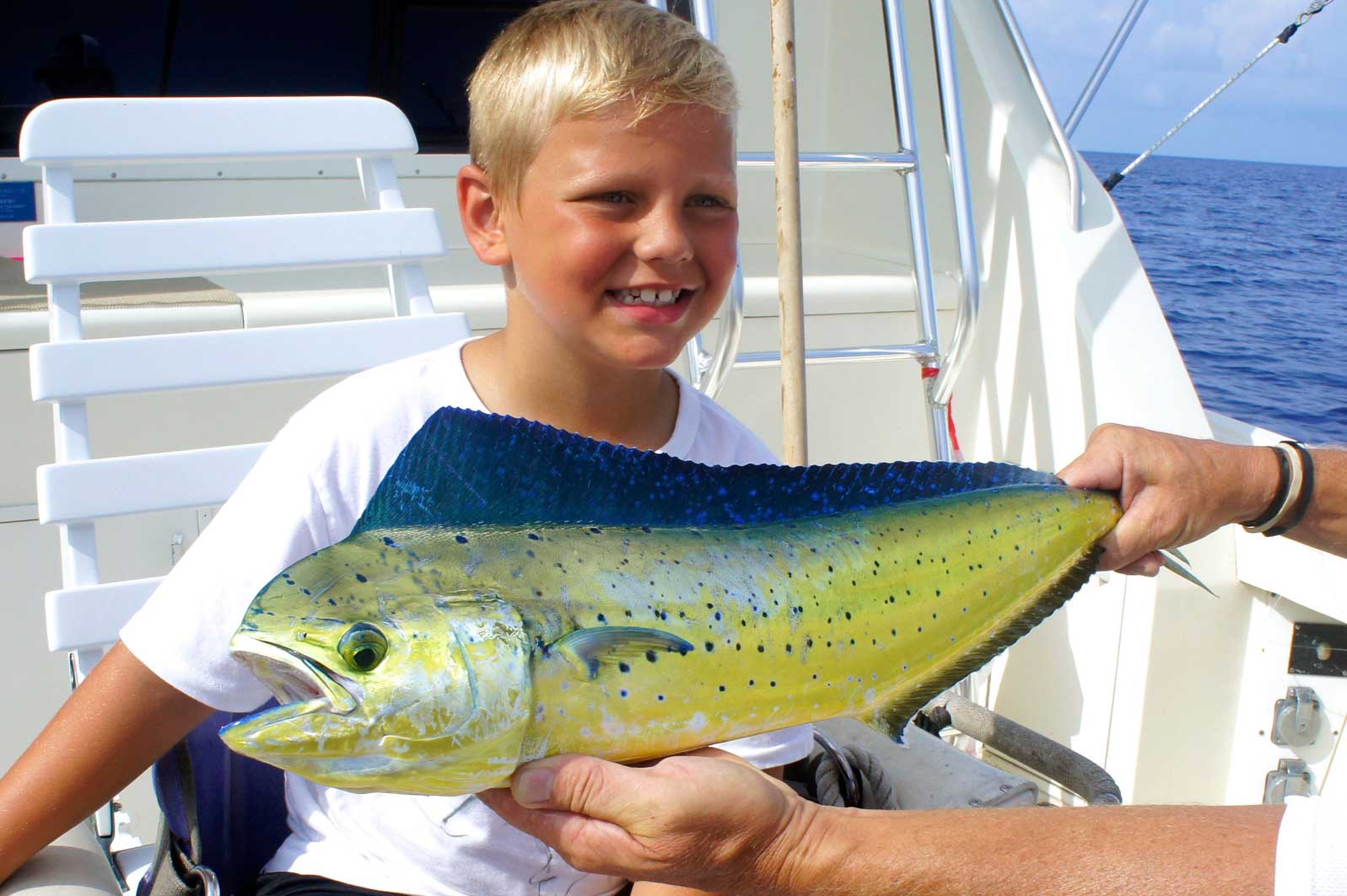 A young boy is holding a fish in his hands on a boat